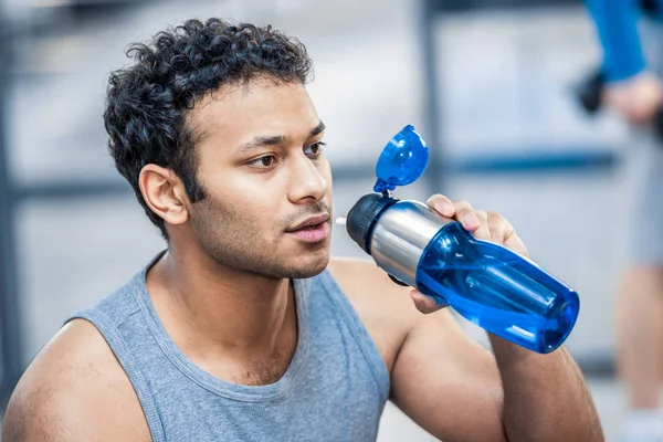 Homem com garrafa de água descansando no ginásio — Fotografia de Stock