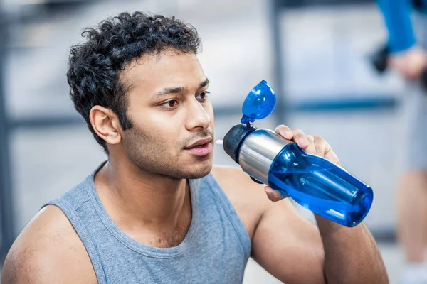 Man with bottle of water resting at gym — Stock Photo