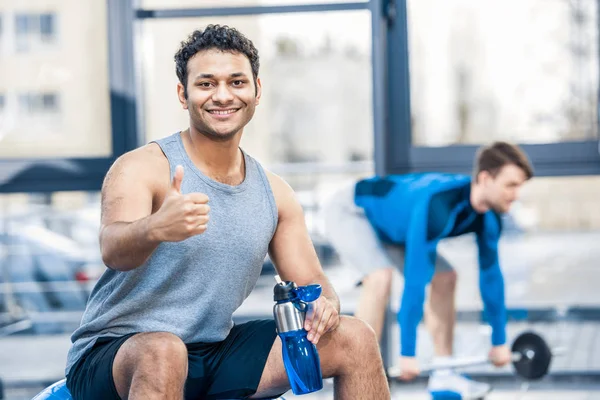Homme avec bouteille d'eau reposant à la salle de gym — Photo de stock