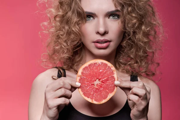 Woman holding piece of grapefruit — Stock Photo