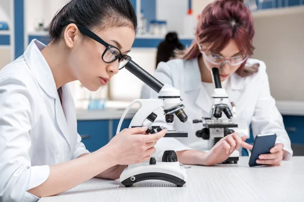 Cientistas que trabalham em conjunto com microscópios — Fotografia de Stock