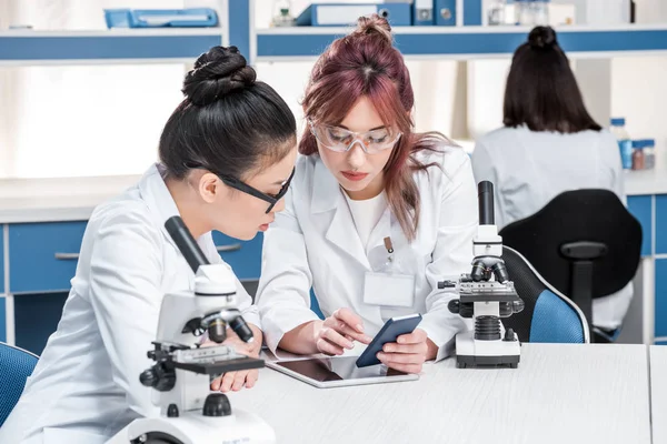 Científicos que trabajan juntos con microscopios - foto de stock