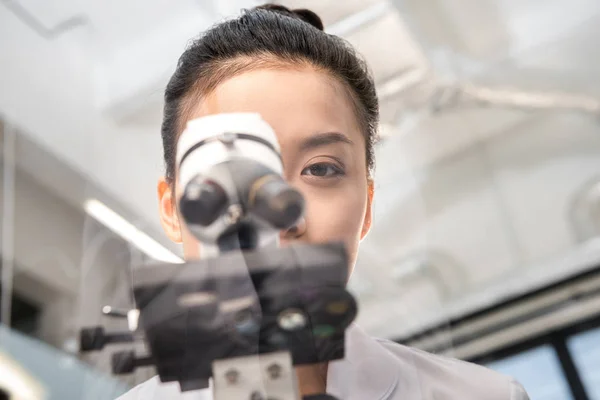 Scientist looking through microscope — Stock Photo