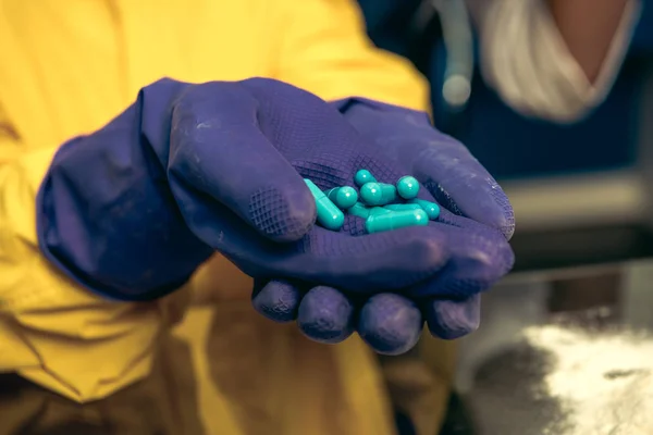 Mains dans des gants en caoutchouc tenant des pilules — Photo de stock