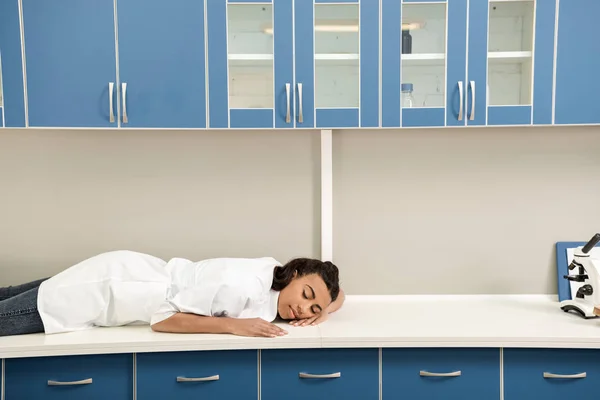 Chica científica durmiendo en mesa en laboratorio - foto de stock