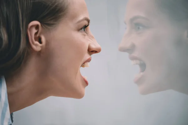 Stressed woman screaming at reflection — Stock Photo