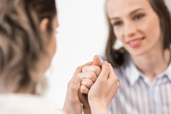 Girlfriends sitting and holding hands — Stock Photo