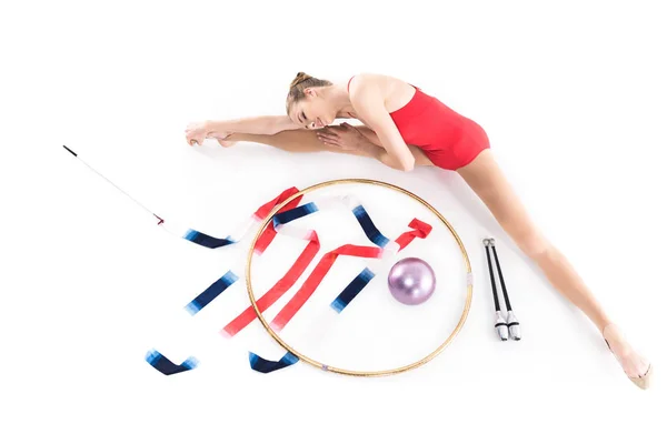 Девушка растягивается рядом с аппаратом для художественной гимнастики — стоковое фото