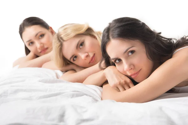 Young beautiful women lying on bed — Stock Photo