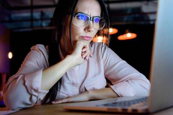 Donna d'affari pensierosa in occhiali guardando il computer portatile — Foto stock