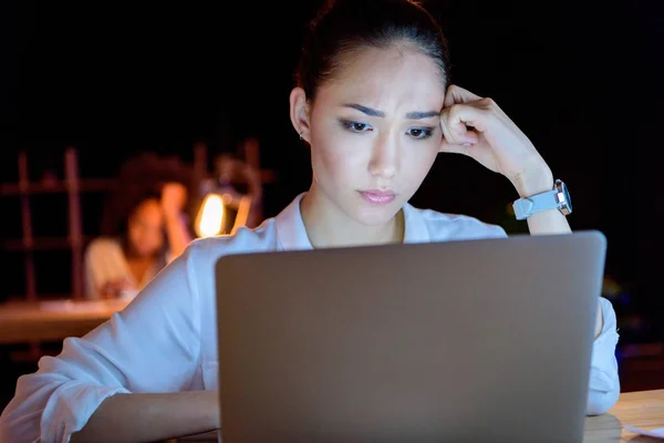 Pensive asian businesswoman working on laptop — Stock Photo