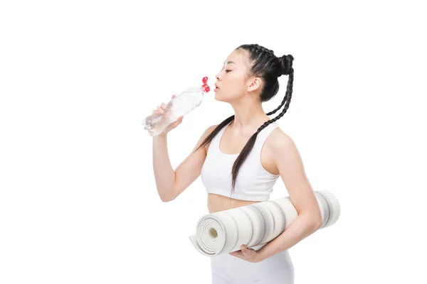 Chica con estera de yoga agua potable - foto de stock