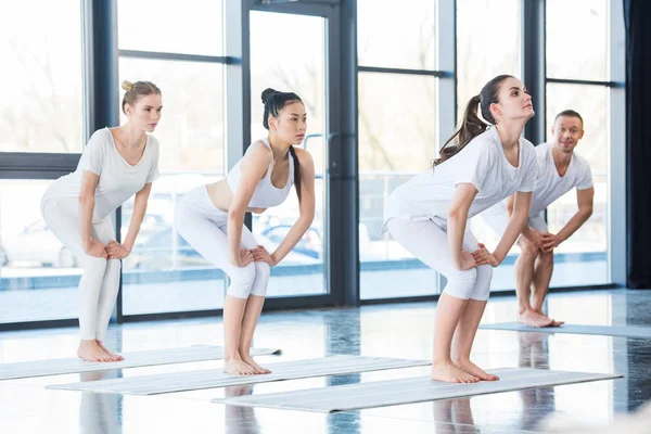 Mulheres fazendo pose cadeira com instrutor — Fotografia de Stock