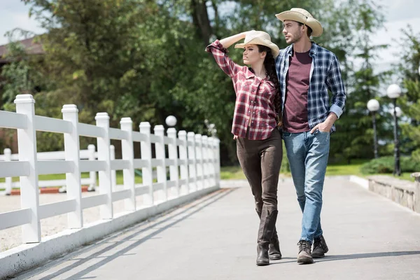 Vaquero con novia caminando por el camino en el parque - foto de stock