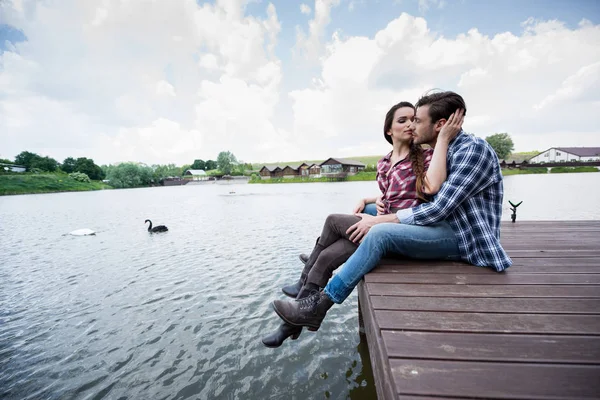 Young couple sitting on wooden pier — Stock Photo