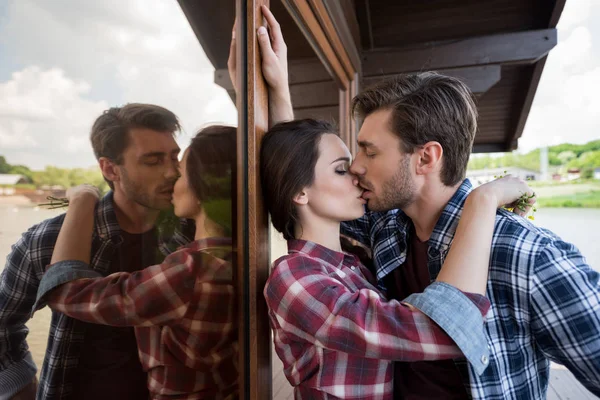 Jeune caucasien couple baisers près fenêtre — Photo de stock