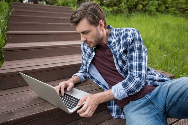 Uomo casuale che utilizza il computer portatile al parco — Foto stock