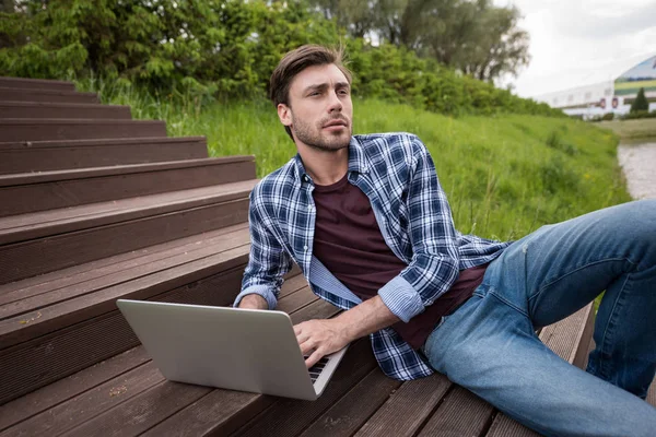 Homem casual usando laptop no parque — Fotografia de Stock