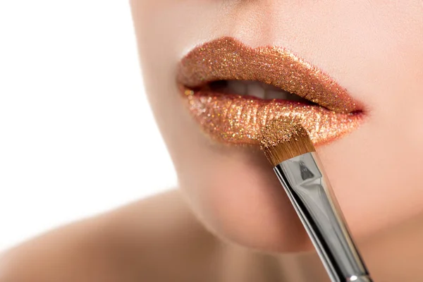 Mujer aplicando lápiz labial dorado - foto de stock