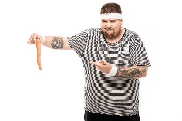 Fat man pointing with finger at carrot — Stock Photo