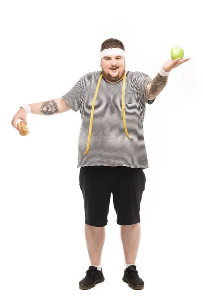 Hombre gordo sosteniendo hamburguesa y manzana - foto de stock