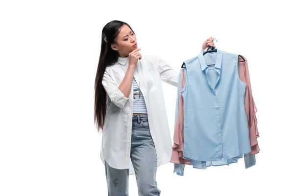 Asian girl choosing blouses — Stock Photo