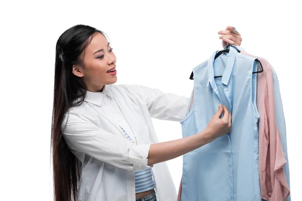 Asian girl choosing blouses — Stock Photo