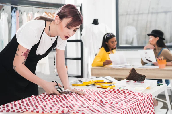 Dressmaker cutting fabric with scissors — Stock Photo