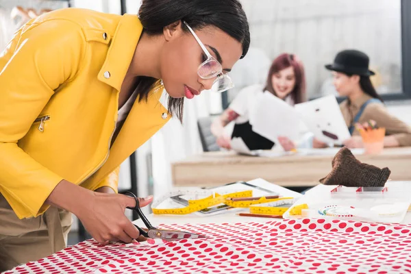 Young dressmaker cutting fabric — Stock Photo