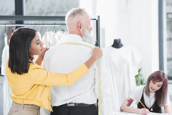 Tailor measuring grey haired man — Stock Photo