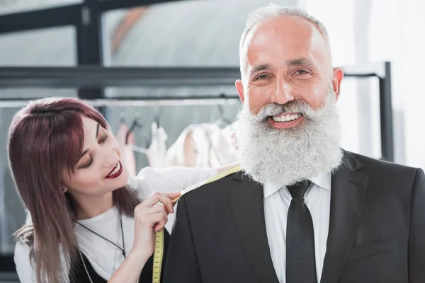 Tailor fitting smiling elderly man — Stock Photo