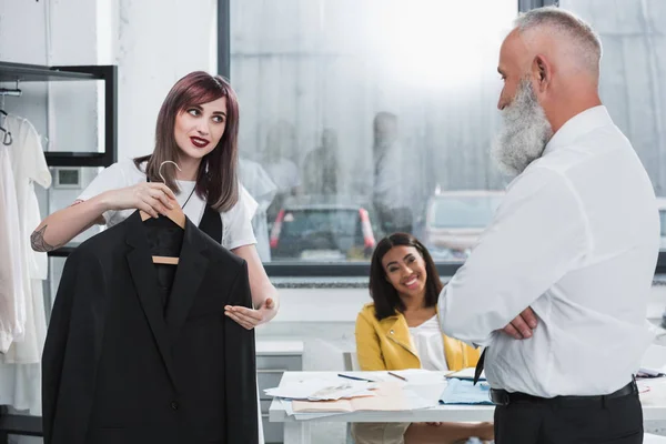 Tailor proposing man to try on jacket — Stock Photo