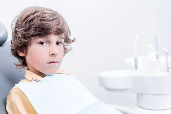 Niño sentado en silla de dentista - foto de stock