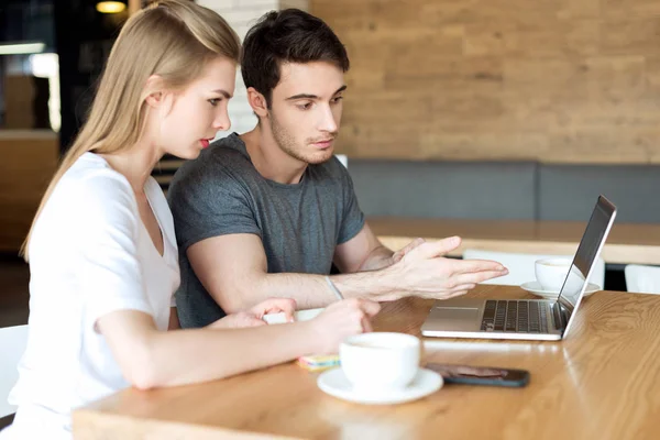 Pareja trabajando en el ordenador portátil en la cafetería - foto de stock