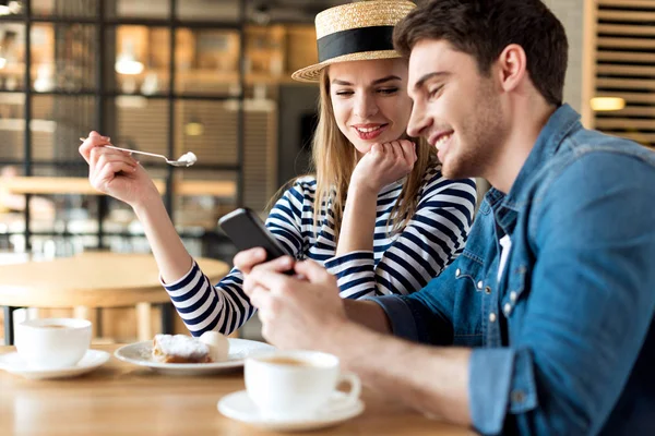 Пара, использующая смартфон в кафе — стоковое фото