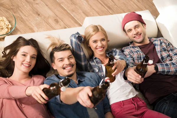 Happy young friends lying on sofa — Stock Photo