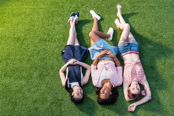Chicas multiétnicas tumbadas en la hierba - foto de stock