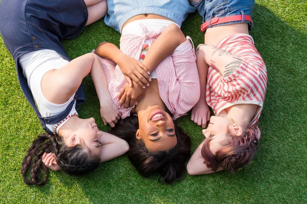 Chicas multiétnicas tumbadas en la hierba - foto de stock