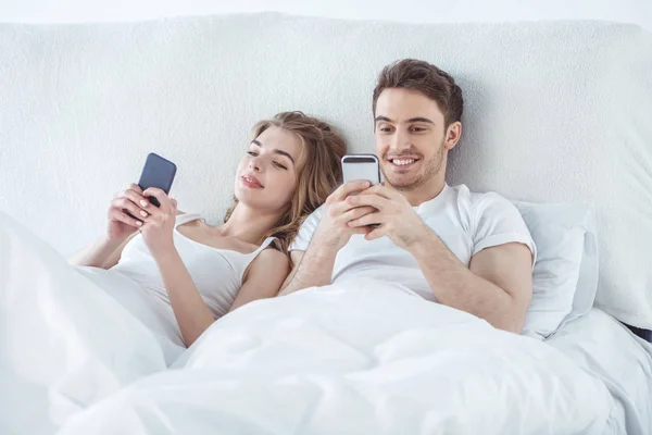 Pareja usando teléfonos inteligentes - foto de stock