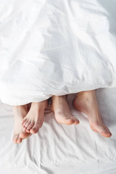 Pieds de couple couché au lit — Photo de stock