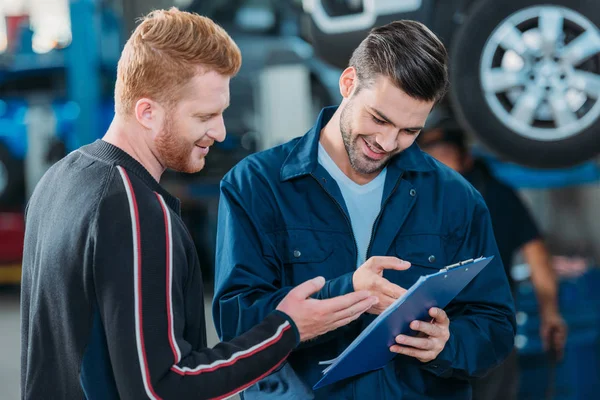 Automechanic showing client clipboard — Stock Photo