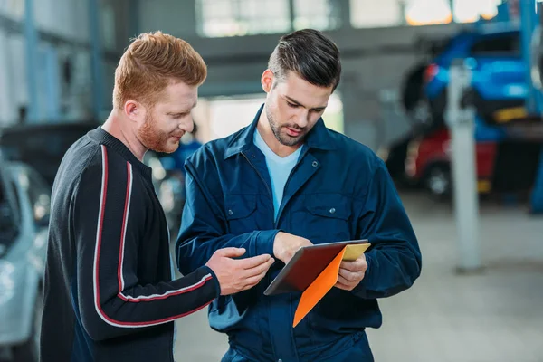 Automechanic and client looking digital tablet — Stock Photo