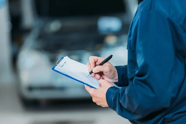 Automechanic writing on clipboard — Stock Photo