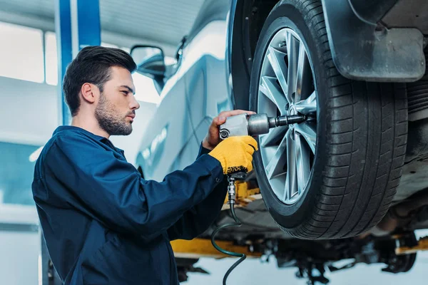 Automechanic unscrewing tire bolts — Stock Photo