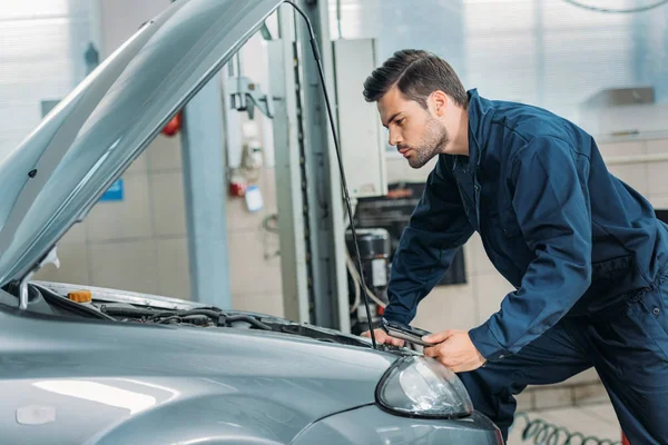 Automechanic looking under car hood — Stock Photo