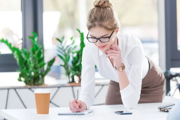 Empresaria escribiendo en bloc de notas - foto de stock