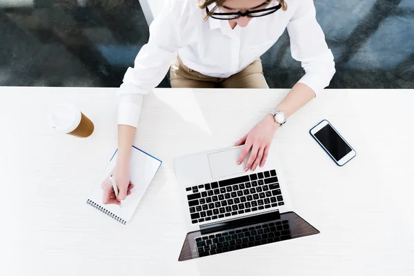 Mujer de negocios que trabaja con portátil y teléfono inteligente - foto de stock