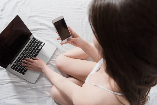 Woman with smartphone using laptop — Stock Photo