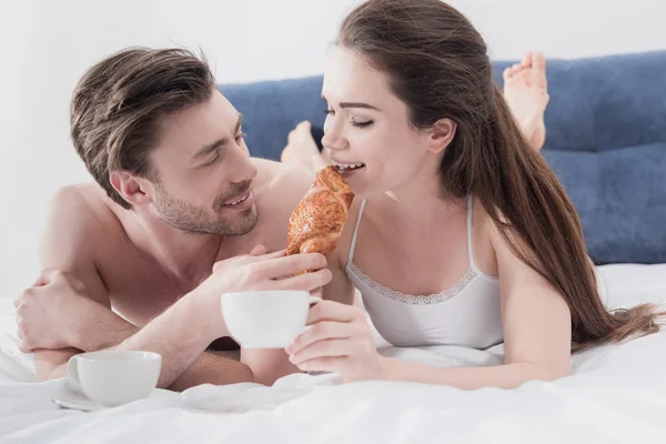 Hombre alimentar a su novia en la cama - foto de stock