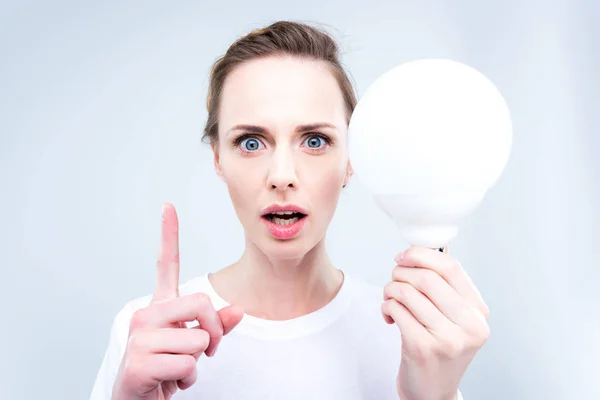 Woman with light bulb pointing up — Stock Photo